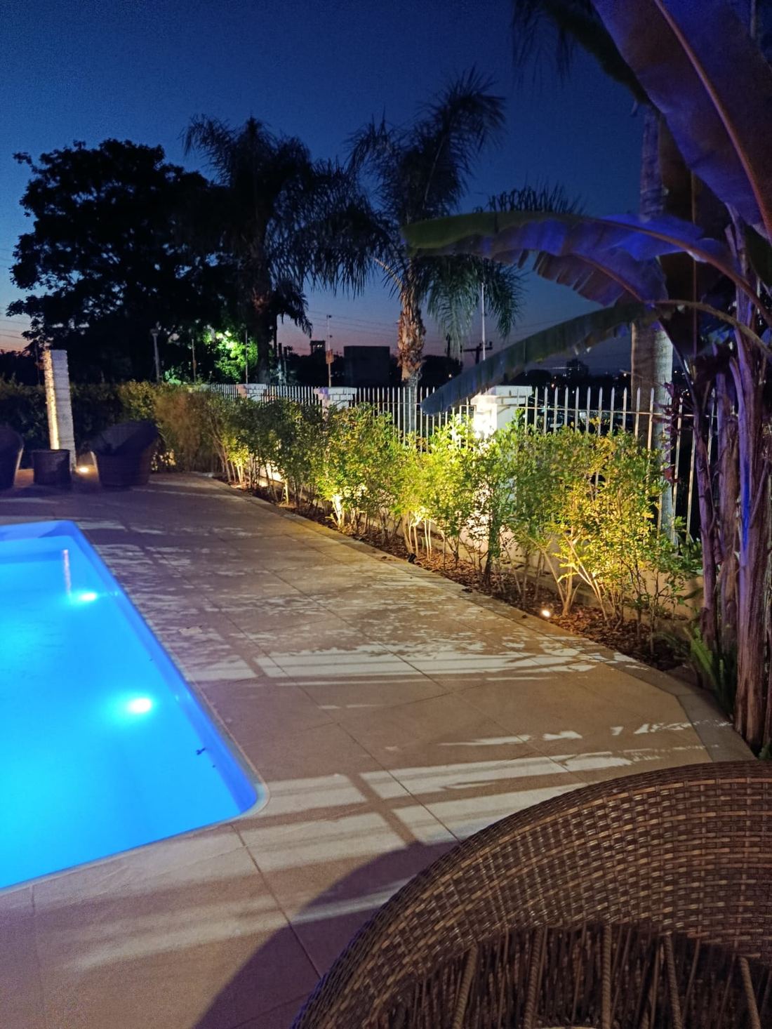 Borda de piscina e canteiro iluminado à noite